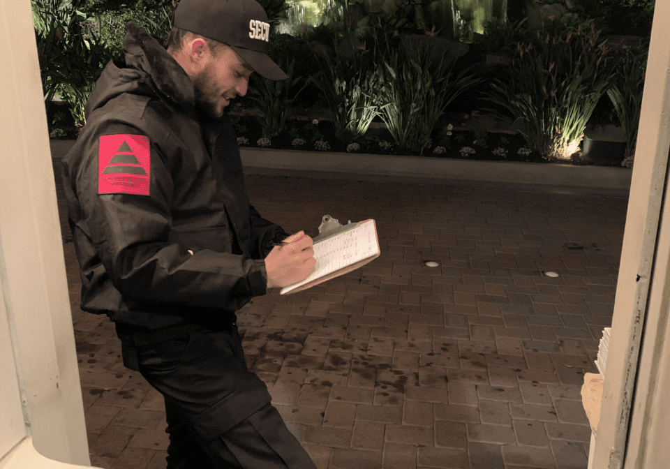 A man in black jacket holding papers and walking.